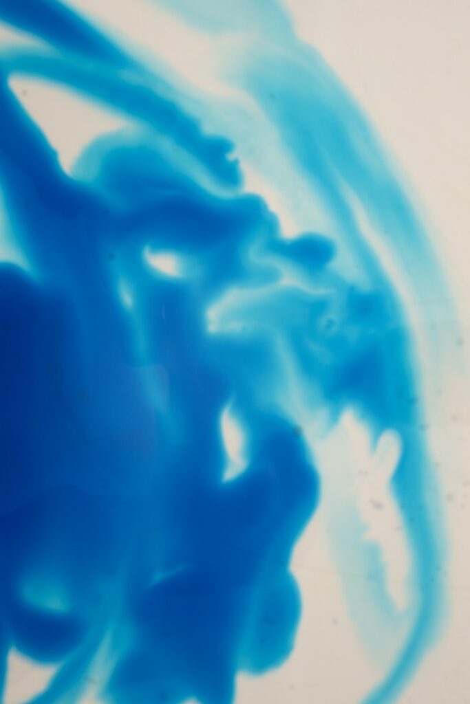 Abstract background of bright blue color ink diffusing slowly in clear water on white background